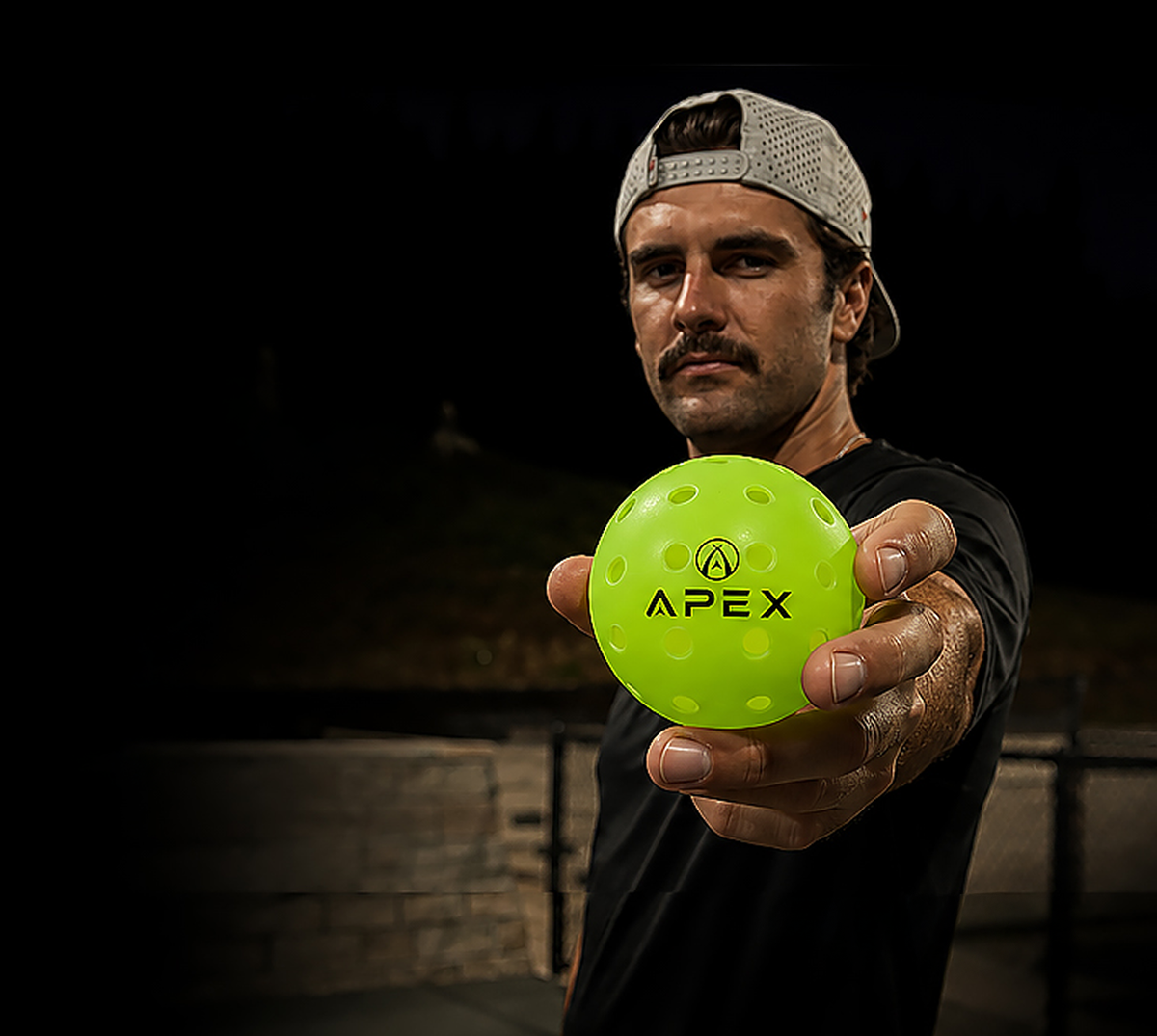 Daniel Traxler holding an APEX pickleball toward the camera